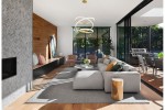 Lampa wisząca Enzo 1xLED/58W w kolorze złotym, umieszczona w nowoczesnym wnętrzu. Posiada charakterystyczny, okrągły kształt z dwoma złożonymi pierścieniami, wisząca nad szarym dywanem w strefie wypoczynkowej.