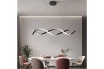 Czarna lampa wisząca Jersey z pilotem, z jedną żarówką LED 21W, w kształcie falującej linii. Zawieszona nad okrągłym stołem w nowoczesnej aranżacji, z jasnym tłem i delikatnymi roślinami w otoczeniu.