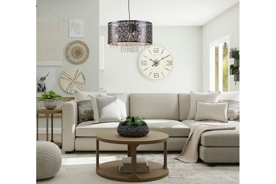 Lampa wisząca Hissa 4xE27 w kolorze czarnym, okrągła, zawieszona nad stołem w jasnym wnętrzu. Wzór z przezroczystymi detalami, otoczona nowoczesnym wystrojem, w tym zegarem ściennym i roślinami.
