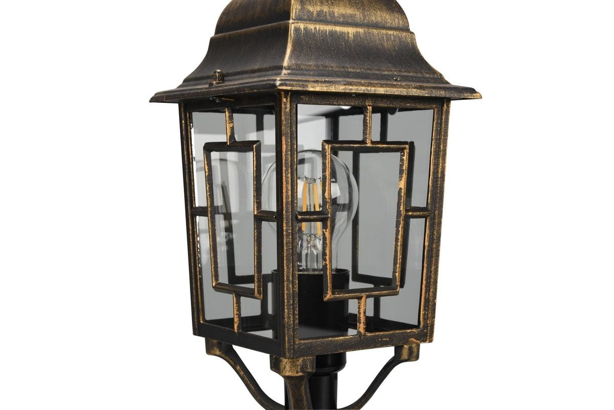 Lampa stojąca ogrodowa Volturno H47,5 cm, w antycznej rdzy, z kloszem w kształcie latarni. Widoczne prostokątne elementy dekoracyjne oraz żarówka E27. Ujęcie z boku, ukazujące detal konstrukcji i materiału.