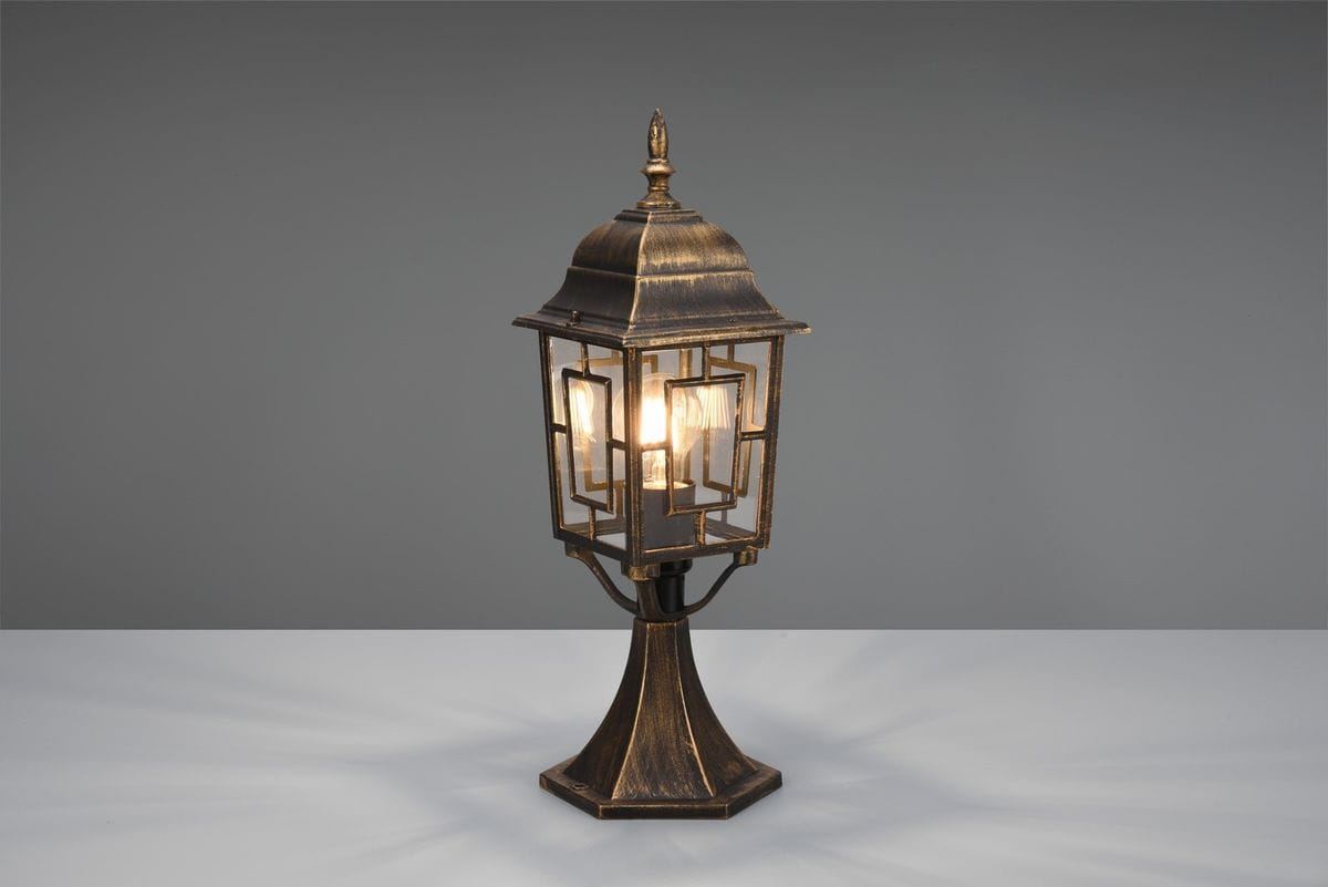 Lampa stojąca ogrodowa Volturno H47,5 w kolorze antycznej rdzy, z dekoracyjnym kloszem i podstawą w kształcie ośmiokąta. Ujęcie z boku, z widocznym źródłem światła E27 wewnątrz klosza. Tło w odcieniu szarym.