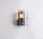 Kinkiet zewnętrzny Hoosic w kolorze czarnym z przydymionym kloszem, z czujnikiem ruchu. Wymiary: średnica 85 mm, wysokość 175 mm, szerokość 118 mm. Produkt zamontowany na ścianie, świecący ciepłym światłem.