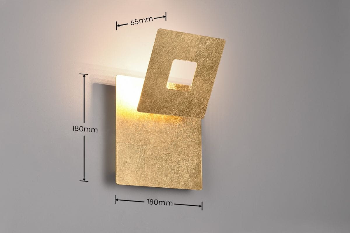 Kinkiet Leano w kolorze złotym, z podświetleniem LED 6W. Ma kwadratowy kształt z otworem w górnej części. Wymiary: 180 mm x 180 mm, grubość 65 mm. Produkt montowany na ścianie, na jasnym tle.