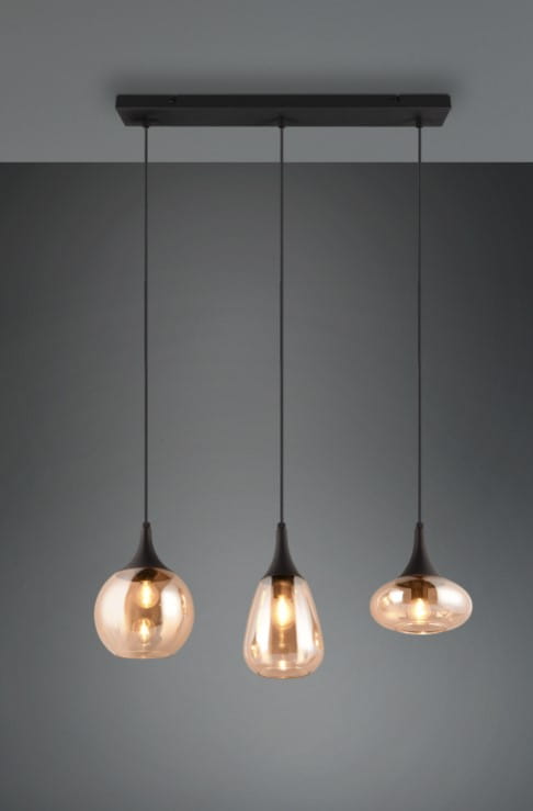 Lampa wisząca Lumina z trzema kloszami E14, czarna konstrukcja z bursztynowymi szklanymi kloszami w różnych kształtach. Zawieszona na cienkich linkach, idealna do nowoczesnych wnętrz. Tło w odcieniu szarości.