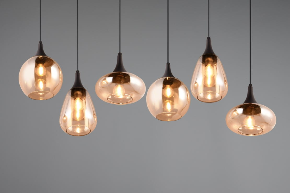Lampa wisząca Lumina z sześcioma kloszami E14 w kształcie kropli, wykonana z bursztynowego szkła, z czarnymi metalowymi elementami. Wisi na cienkich linkach, prezentując nowoczesny design na szarym tle.