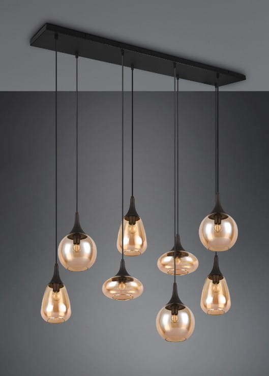 Lampa wisząca Lumina z 8 kloszami E14, czarna podstawa z metalowymi zawieszeniami. Klosze w kształcie kropli, bursztynowe, z przezroczystym wykończeniem, zawieszone na różnych wysokościach na tle szarej ściany.