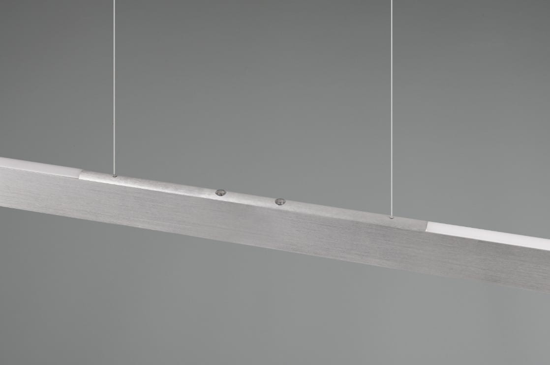 Lampa wisząca Helios z aluminium, w formie prostokątnej belki, z zamontowanym źródłem światła LED o mocy 28W. Ujęcie z boku, zawieszona na cienkich linkach. Metaliczna, szczotkowana powierzchnia, minimalistyczny design.