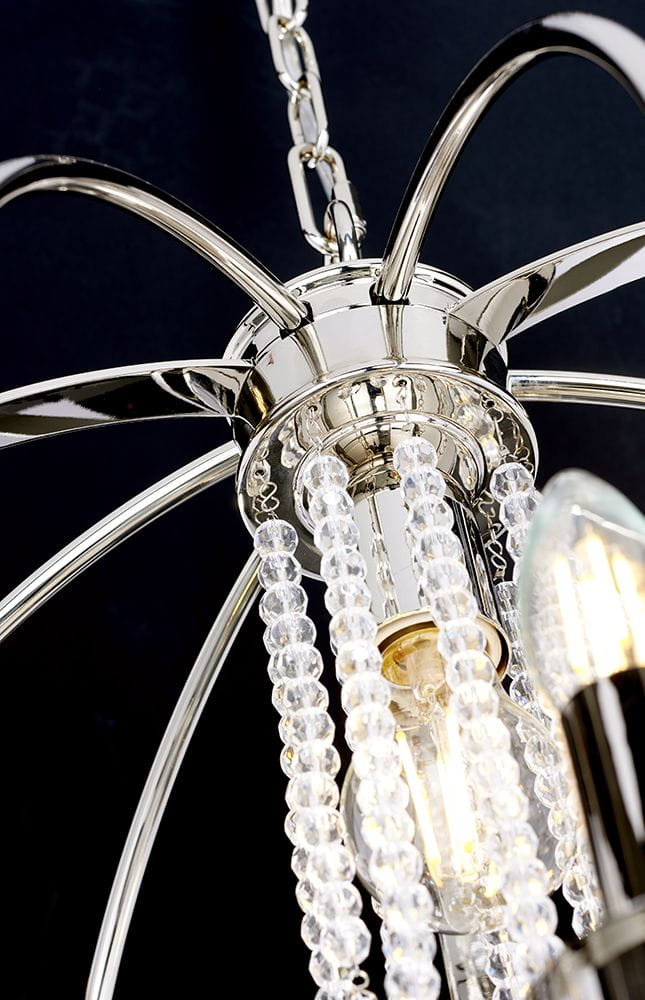 Lampa wisząca Cassie z chromowanym wykończeniem, z trzema gniazdami E14 i jednym E27. Posiada dekoracyjne szklane koraliki, które zwisają z centralnej części. Kąt ujęcia z góry, ukazujący detale zawieszenia oraz źródła światła.