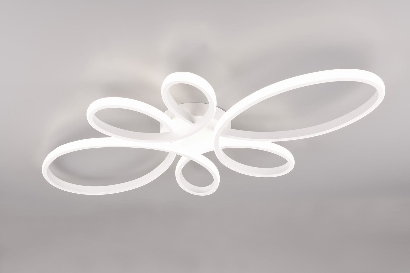 Lampa sufitowa Fly o białej obudowie, złożona z wielokrotnych, okrągłych kształtów. Ujęcie z góry, ukazujące płaską podstawę oraz podświetlane pierścienie. Stylowy design, idealna do nowoczesnych wnętrz. Wymiary i detale konstrukcyjne nie są widoczne.