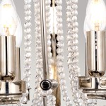 Lampa wisząca Cassie z polerowanego niklu, z sześcioma gniazdami E14 i jednym E27. W centralnej części metalowa konstrukcja, otoczona kryształowymi koralikami, które odbijają światło. Kąt ujęcia zbliżeniowy, ukazujący detale wykończenia.