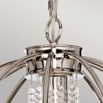 Lampa wisząca Cassie w polerowanym niklu z sześcioma oprawami E14 i jedną E27. U góry widoczny okrągły uchwyt, z którego zwisają przezroczyste kryształki, dodające elegancji. Produkt zawieszony na cienkim kablu.