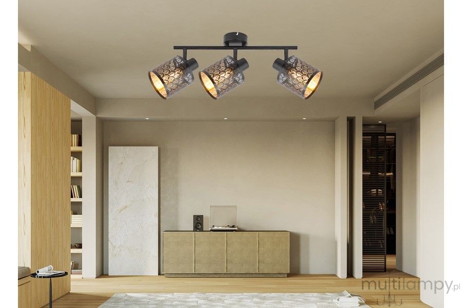 Lampa sufitowa Tuluza w kolorze czarnym, z trzema reflektorami E14. Reflektory mają dekoracyjne, metalowe klosze z wzorem, zamontowane na prostokątnym stelażu. Produkt umieszczony w nowoczesnym wnętrzu, na tle minimalistycznego mebla.