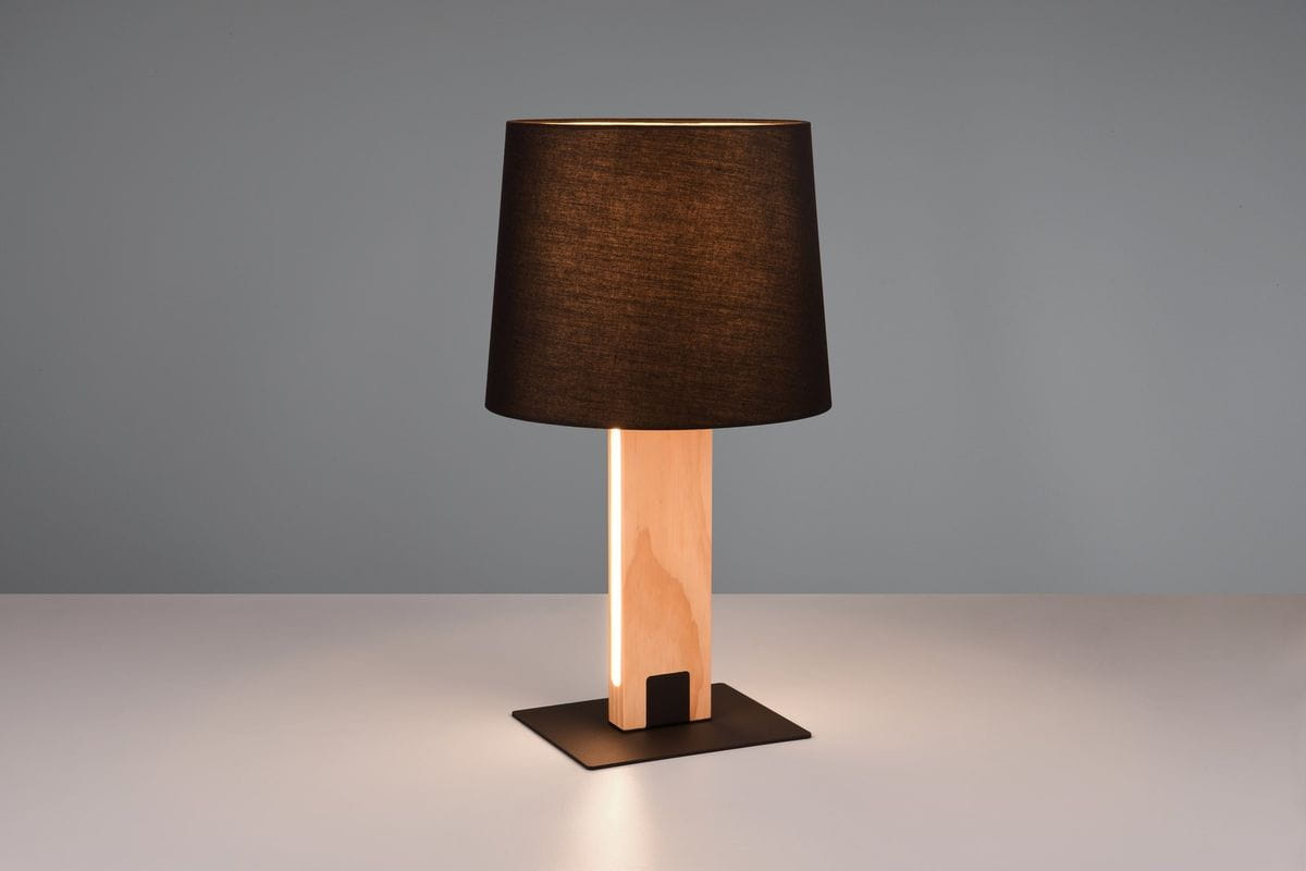 Lampa stołowa Rahul z czarnym abażurem i jasnym drewnem, z podstawą w kształcie kwadratu. Ujęcie frontalne, ukazujące lampę w pozycji stojącej, z widocznym źródłem światła LED oraz miejscem na żarówkę E27. Tło w odcieniach szarości.