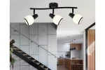 Czarna lampa sufitowa Loris z trzema reflektorami E14. Okrągłe, matowe klosze w białym kolorze, zamontowane na łukowatej, czarnej oprawie. Lampa umieszczona w nowoczesnym wnętrzu, nad schodami, z widokiem na kuchnię w tle.