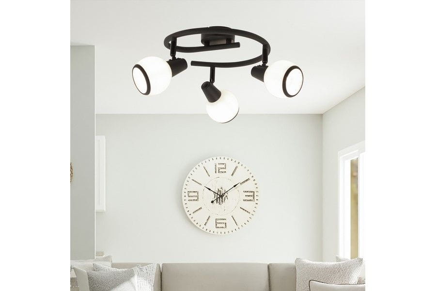 Lampa sufitowa Loris z trzema punktami świetlnymi E14 w kolorze czarnym. Każdy klosz ma biały, okrągły kształt z czarnym wykończeniem. Zainstalowana na okrągłej podstawie, w aranżacji nowoczesnego wnętrza z zegarem na ścianie.