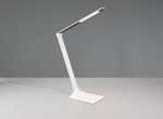 Lampka biurkowa Travis w kolorze białym, wykonana z metalu. Posiada elastyczny, prostokątny klosz LED o mocy 6,5W, zamocowany na smukłej, białej nodze. Wyposażona w port USB-C, ustawiona na płaskiej podstawie, z widocznym kablem zasilającym.
