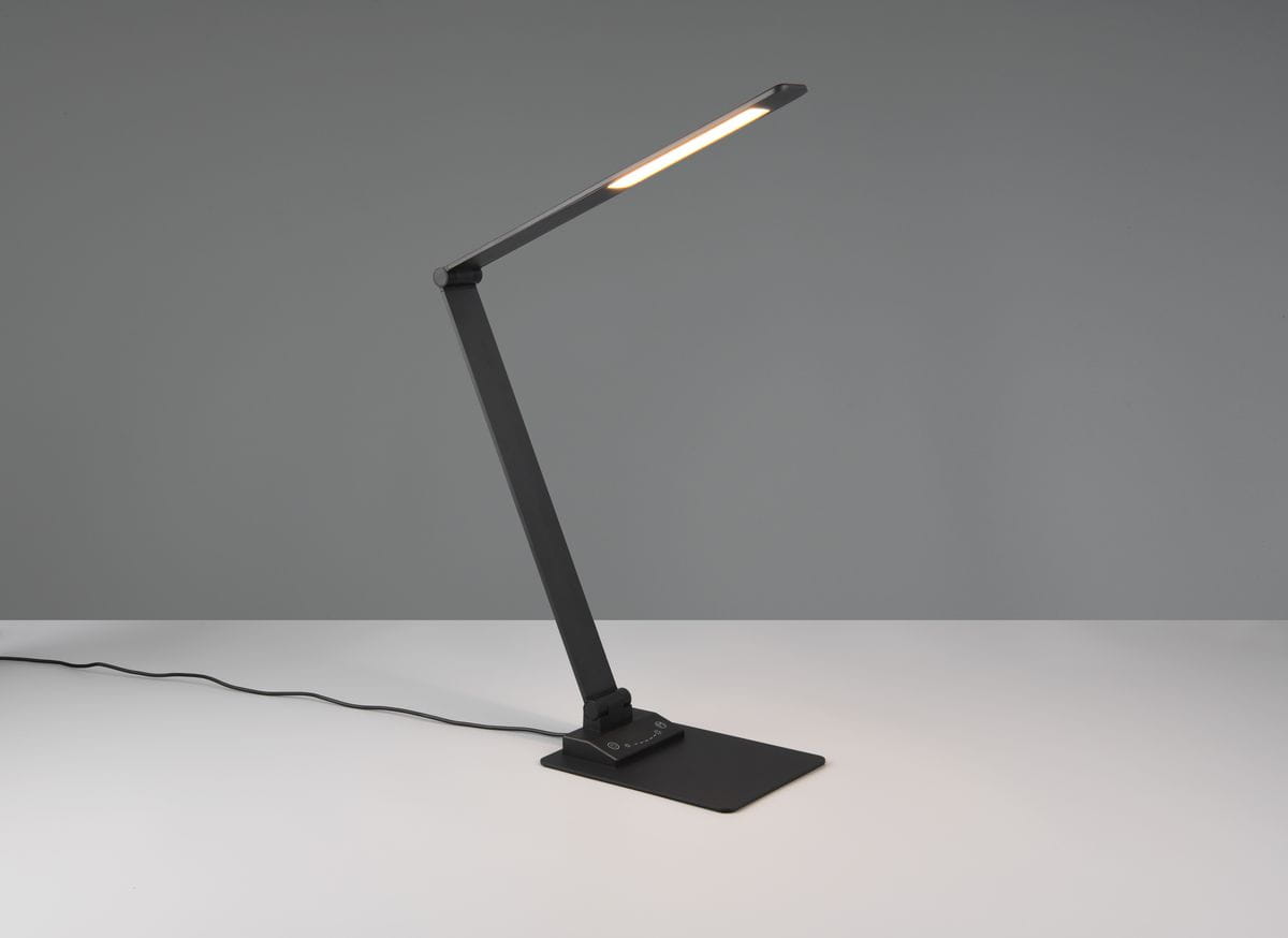 Lampka biurkowa Travis w kolorze czarnym, z regulowanym ramieniem, z wbudowanym portem USB-C. Kąt ujęcia z boku, na jednolitym tle. Widoczna podstawa oraz źródło światła LED o mocy 6,5W.