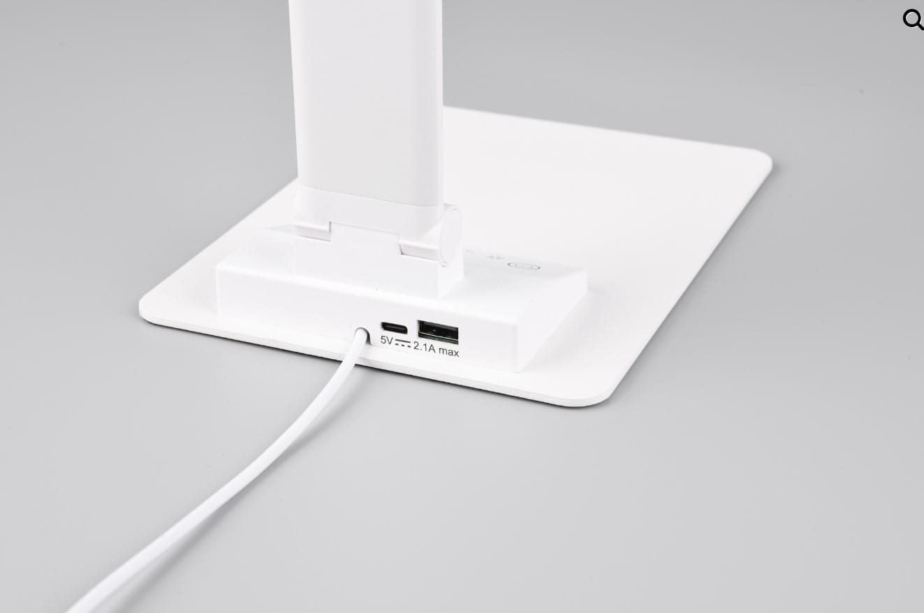 Lampka biurkowa Travis w kolorze białym z portem USB-C, posiadająca jedną diodę LED o mocy 6,5W. Ujęcie z boku pokazuje podstawę z widocznym portem USB i kablem. Prosta, nowoczesna konstrukcja, idealna do biura lub na biurko.