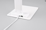 Lampka biurkowa Travis w kolorze białym z portem USB-C, posiadająca jedną diodę LED o mocy 6,5W. Ujęcie z boku pokazuje podstawę z widocznym portem USB i kablem. Prosta, nowoczesna konstrukcja, idealna do biura lub na biurko.