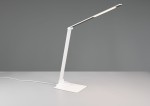 Lampka biurkowa Travis w kolorze białym, z elastycznym ramieniem i płaską podstawą. Posiada wbudowany port USB-C, źródło światła LED o mocy 6,5W. Ujęcie z boku, ukazujące nowoczesny design i funkcjonalność. Kabel zasilający widoczny na stole.