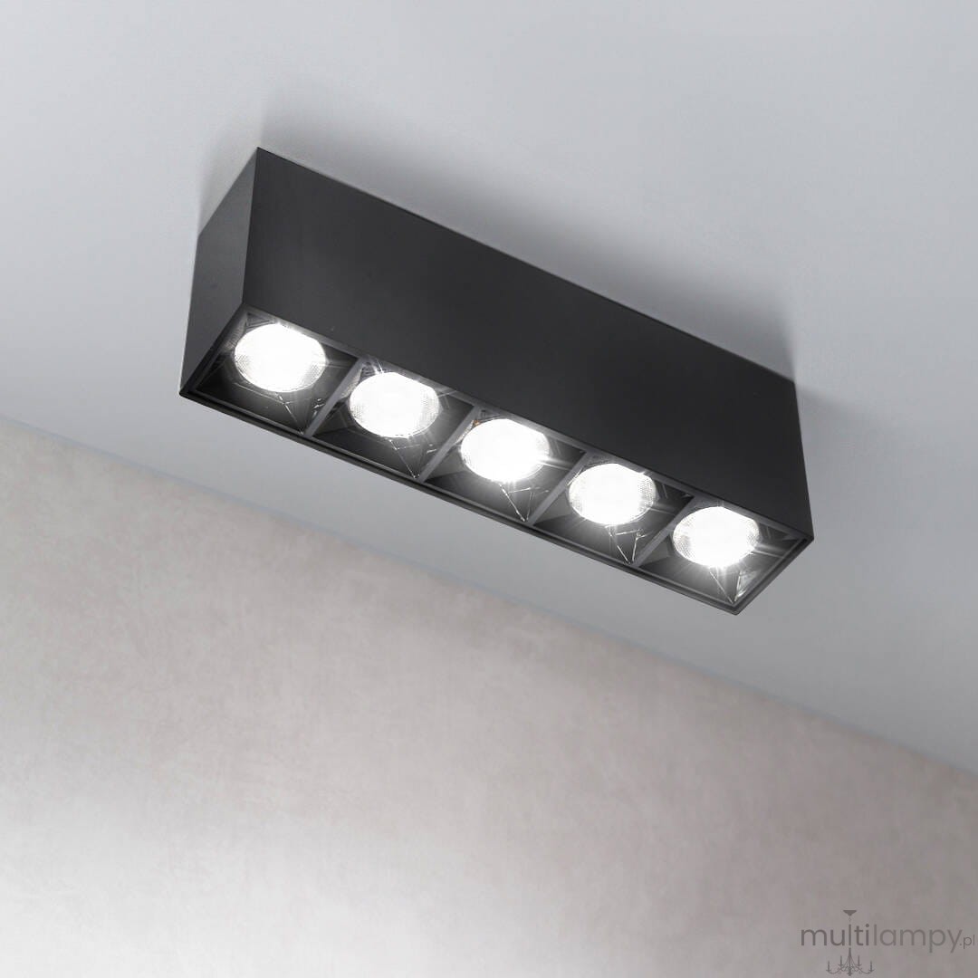 Lampa sufitowa LED w czarnej obudowie, z pięcioma okrągłymi źródłami światła. Zamontowana na suficie, emituje ciepłe światło o temperaturze 3000K. Prosta, prostokątna forma, idealna do nowoczesnych wnętrz.
