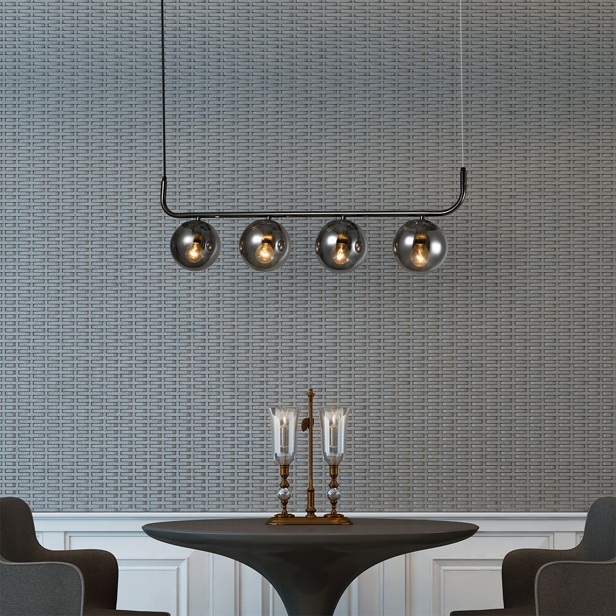 Lampa wisząca Alisa w kolorze grafitowym z czterema dymionymi kloszami w kształcie kul. Ujęcie z góry, zawieszona nad okrągłym stołem, na tle strukturalnej ściany. W widoku także stylowe świeczniki z przezroczystymi lampionami.