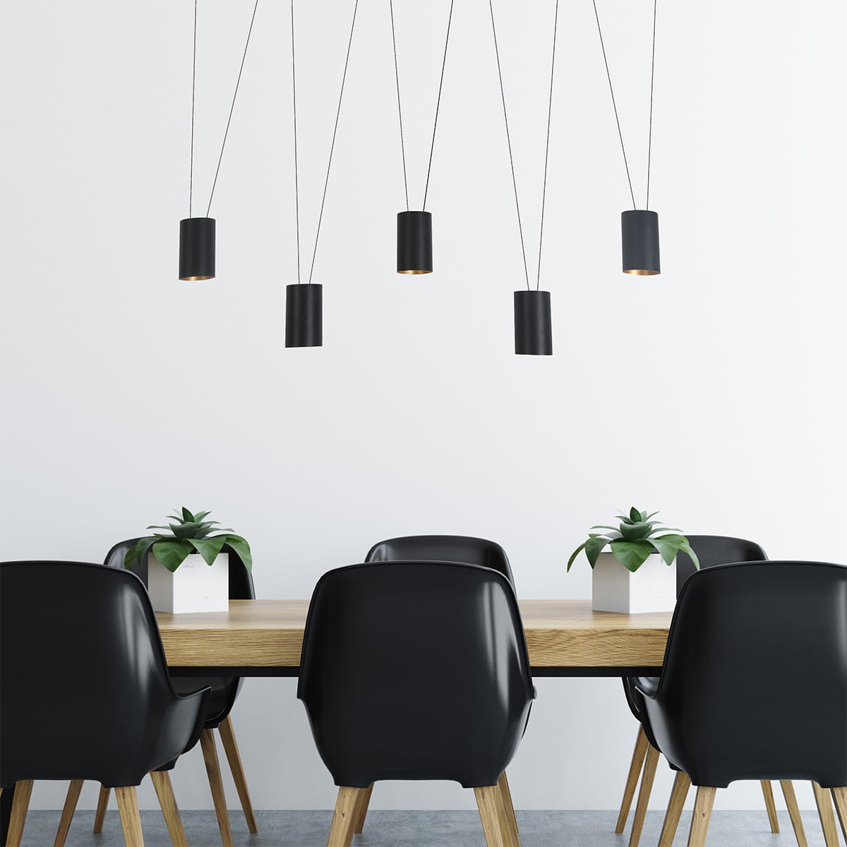 Czarna lampa wisząca Toledo z pięcioma oprawami GU10, zawieszona na cienkich linkach, w aranżacji nad drewnianym stołem z czarnymi krzesłami. W tle białe ściany i roślina w doniczce.