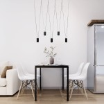 Czarna lampa wisząca Toledo z pięcioma oprawami GU10, zawieszona na cienkich linkach, nad prostokątnym stołem w jasnym wnętrzu. W tle białe krzesła i szafka, na stole wazon z gałązką.
