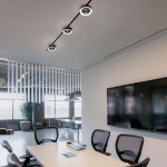 Lampa LED z wiatrakiem na szynie magnetycznej, czarna, z pilotem, 12W, 4000K. Produkt zamontowany na suficie, z widocznymi trzema okrągłymi źródłami światła i wentylatorem, w nowoczesnym biurze z dużymi oknami i minimalistycznym wystrojem.