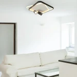 Czarna lampa sufitowa Parma z dwoma ruchomymi źródłami światła GU10 i LED, o kwadratowym kształcie. Montowana na suficie, umieszczona w jasnym wnętrzu z białą sofą i szklanym stolikiem.