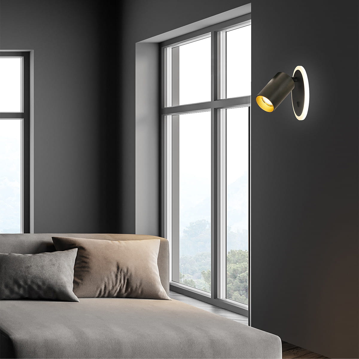 Kinkiet Parma w kolorze czarnym z oprawą GU10 i LED, zamontowany na ciemnej ścianie obok okna. Lampa ma cylindryczny kształt z okrągłą podstawą. Obok widoczna szara sofa z poduszkami, tworząc elegancką aranżację wnętrza.