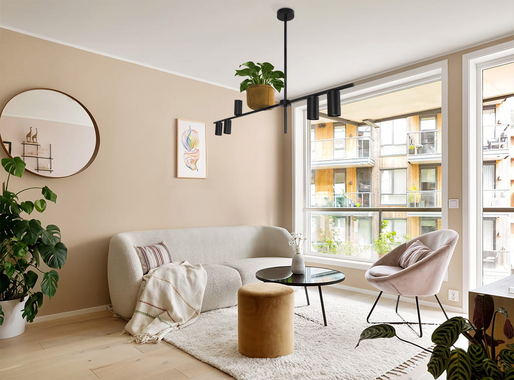 Lampa wisząca Rocco z pięcioma oprawami GU10 w kolorze czarnym, zawieszona w nowoczesnym wnętrzu. Produkt umieszczony nad stolikiem, w otoczeniu roślin i mebli w jasnych tonacjach. Widoczny detal: zielona roślina w doniczce na lampie.