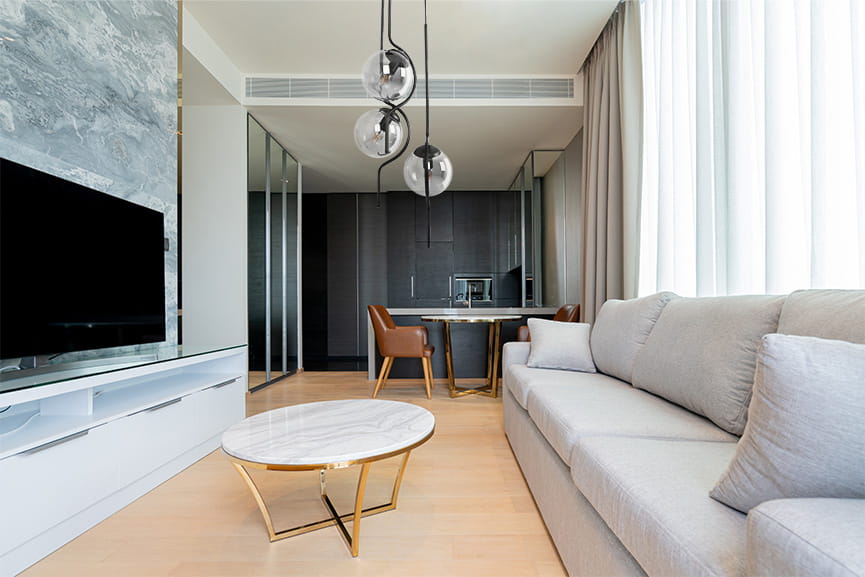 Lampa wisząca Neva w kolorze czarnym i grafitowym, z trzema przezroczystymi kloszami, zawieszona w nowoczesnym wnętrzu. Widok z dołu, z lampą nad stolikiem kawowym w salonie. Elementy dekoracyjne w stylu minimalistycznym.