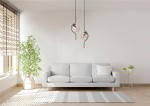 Lampa wisząca Vela 2xE14 w kolorze czarnym z bursztynowymi kloszami, zawieszona nad szarym sofą w jasnym wnętrzu. W tle widoczne okno z roletami i roślina w doniczce.