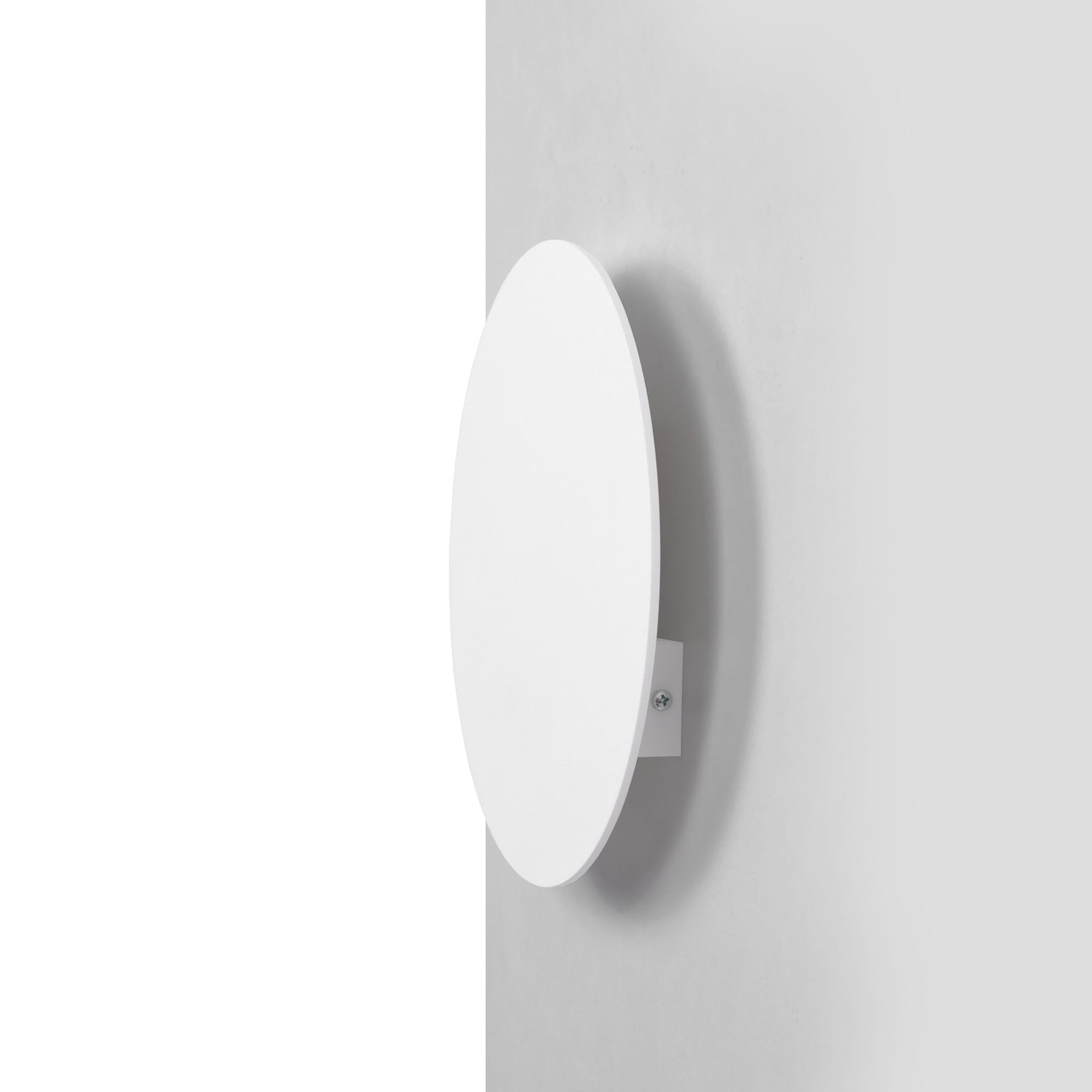Biały kinkiet Pero D25 z okrągłą, płaską obudową, zamontowany na ścianie. Widok z boku, ukazujący minimalistyczny design i metalowy uchwyt. Idealny do nowoczesnych wnętrz.