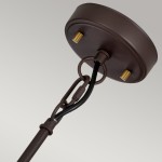 Lampa wisząca Corona w kolorze starym brązie z mocowaniem do sufitu. Posiada miejsce na trzy żarówki E27, widoczne elementy metalowe w kolorze złotym. Kąt ujęcia z góry, ukazujący detale mocowania i przewody.