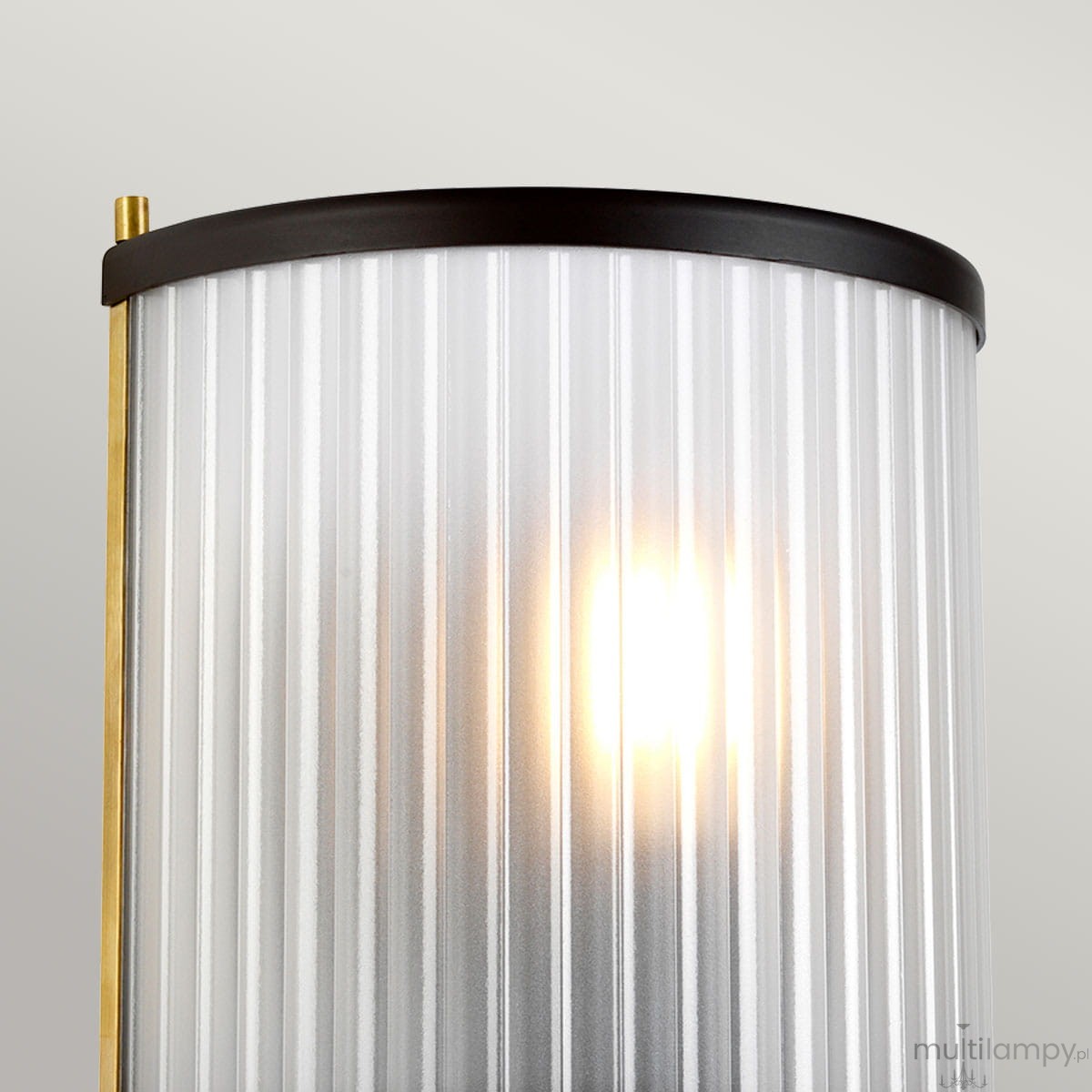 Kinkiet Corona 1xE27 w starym brązie z przezroczystym kloszem w pionowe prążki. Zbliżenie na detal lampy, z widoczną żarówką wewnątrz. Klosz ma zaokrąglony kształt i metalowe wykończenie na górze.