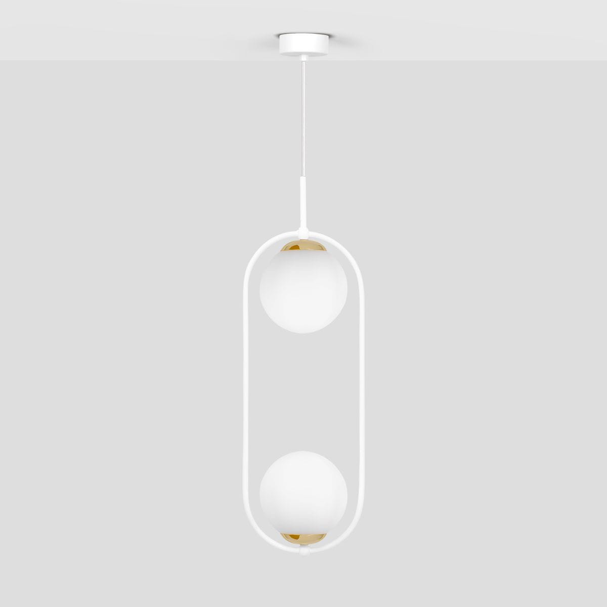 Lampa wisząca Malta 2xE14 w kolorze białym, z dwiema okrągłymi, matowymi kloszami na złotych podstawach, zawieszona na cienkim białym przewodzie. Prosty, nowoczesny design, wisi z sufitu na jednolitym tle.