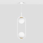 Lampa wisząca Malta 2xE14 w kolorze białym, z dwiema okrągłymi, matowymi kloszami na złotych podstawach, zawieszona na cienkim białym przewodzie. Prosty, nowoczesny design, wisi z sufitu na jednolitym tle.