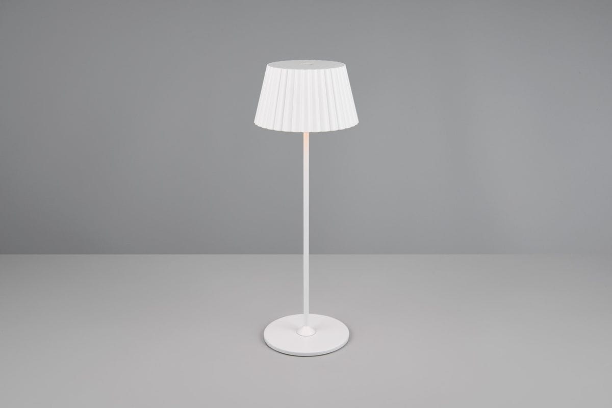Lampa stołowa zewnętrzna Suarez, biała, z kloszem w plisowanym stylu, na cienkiej, prostokątnej nodze. Ujęcie frontalne, produkt stoi na gładkiej powierzchni. Idealna do ogrodu lub na taras, zasilana diodą LED 1,5W.