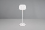 Lampa stołowa zewnętrzna Suarez, biała, z kloszem w plisowanym stylu, na cienkiej, prostokątnej nodze. Ujęcie frontalne, produkt stoi na gładkiej powierzchni. Idealna do ogrodu lub na taras, zasilana diodą LED 1,5W.