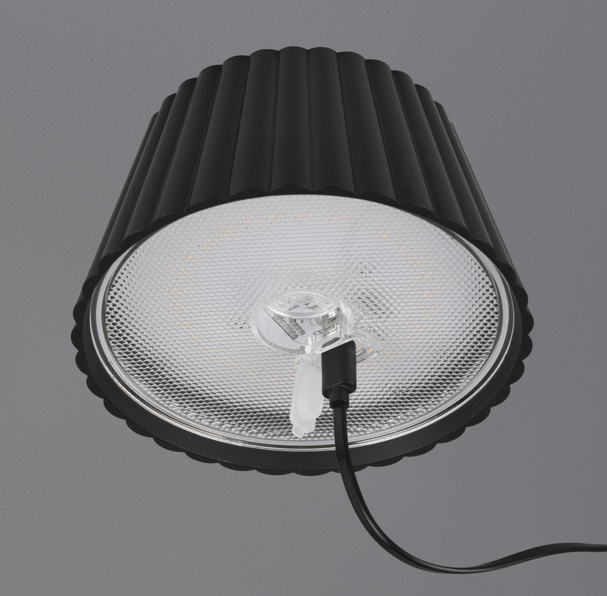 Czarna lampa stojąca zewnętrzna Suarez z kloszem w formie żebrowanego cylindra. Wewnątrz znajduje się dioda LED o mocy 1,5W, widoczne są również przewody zasilające. Ujęcie z góry, pokazujące detal klosza i źródło światła.