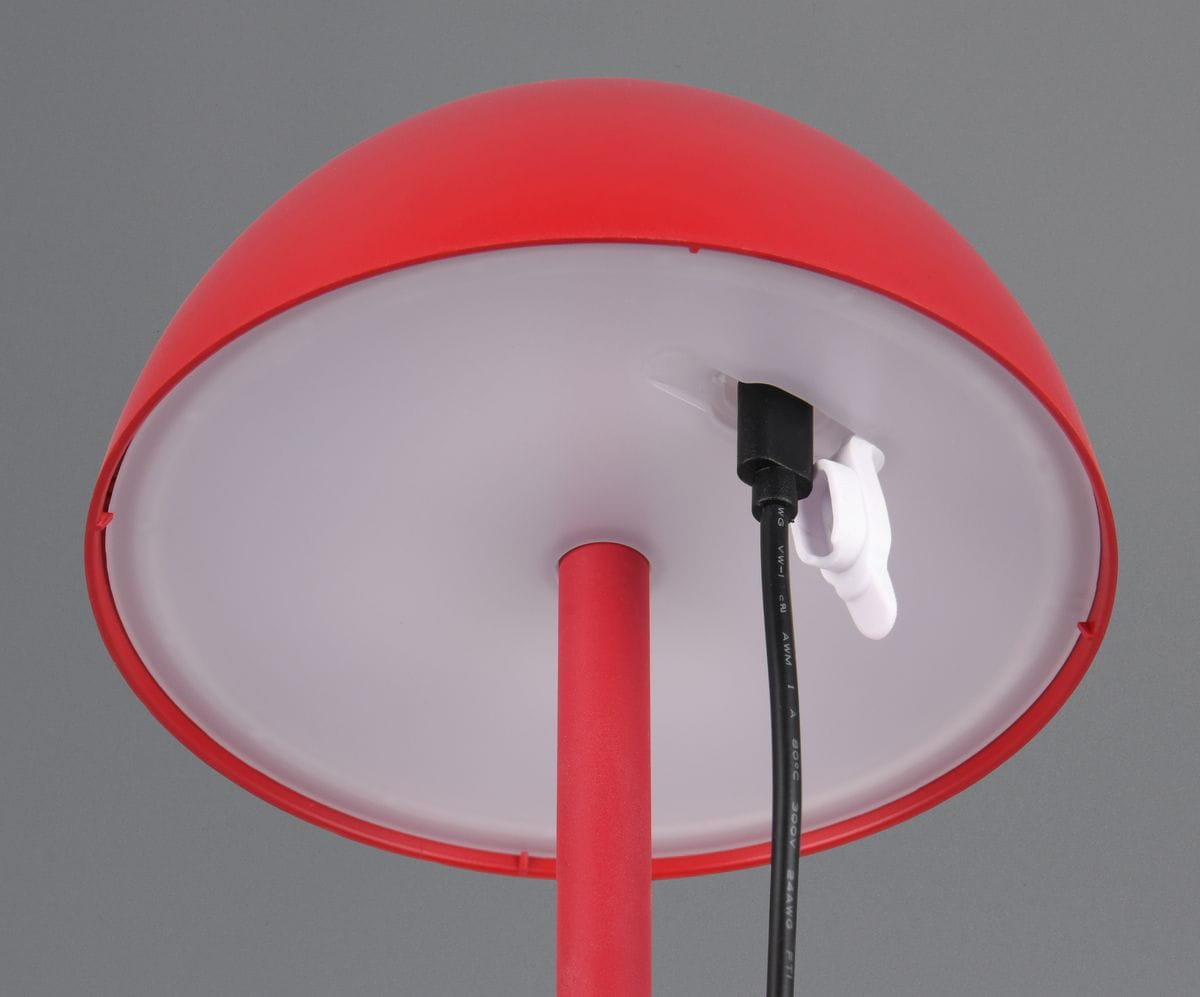 Czerwona lampa stołowa Ricardo, zewnętrzna, z kloszem w kształcie półkuli. Widoczny kabel z wtyczką oraz uchwyt mocujący. Lampa wyposażona w jedno źródło światła LED o mocy 1,5 W. Tło szare, lampa ustawiona w pozycji stojącej.