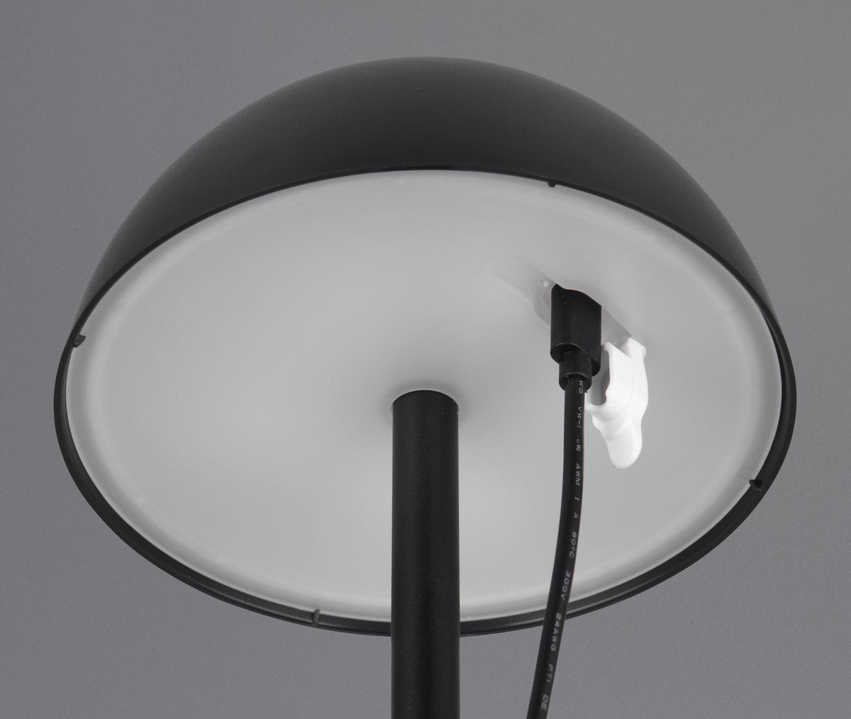 Czarna lampa stołowa zewnętrzna Ricardo z jedną diodą LED (1,5W), widok z góry. Okrągły klosz z matowego materiału, z widocznym przewodem elektrycznym i złączem. Stabilny słupek montażowy. Tło szare.