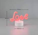 Lampa stołowa Amor w kształcie napisu Love w kolorze różowym, osadzona na białej, okrągłej podstawie. Wymiary: wysokość 140 mm, długość 195 mm, średnica podstawy 85 mm. Idealna do dekoracji wnętrz.