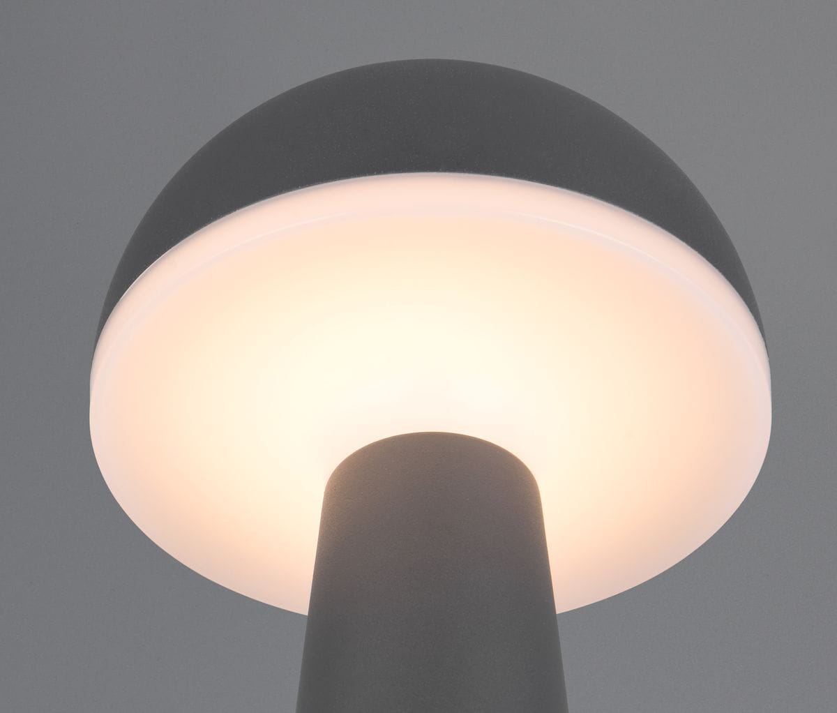 Lampa stołowa Fungo w kolorze antracytowym z okrągłym kloszem, emitującym ciepłe światło. Ujęcie z góry, ukazujące gładki, matowy materiał oraz elegancki kształt. Idealna do użytku na zewnątrz, z jedną diodą LED o mocy 2W.