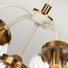 Lampa wisząca Cosmos 5xE14 w antycznej bieli z mosiężnymi detalami. Widoczne eleganckie klosze w kształcie kwiatów oraz dekoracyjne mocowania. Wisi w układzie symetrycznym, prezentując stylowy design.
