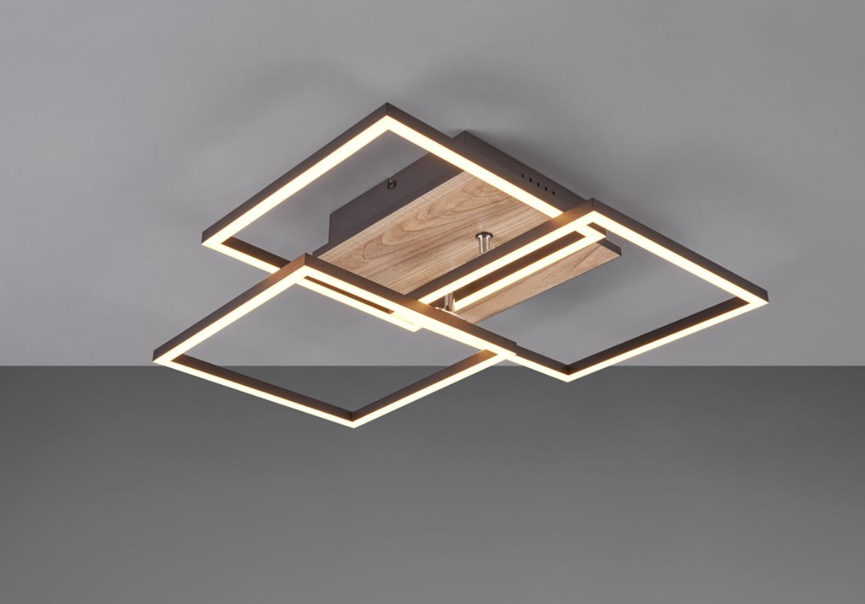 Czarna lampa sufitowa LED 3-punktowa z pilotem, o geometrycznym kształcie z imitacją drewna. Ujęcie z dołu, pokazujące podświetlane ramki w kształcie kwadratów na tle szarym. Lampa zamontowana na suficie, z widocznym detalem drewnianego elementu.