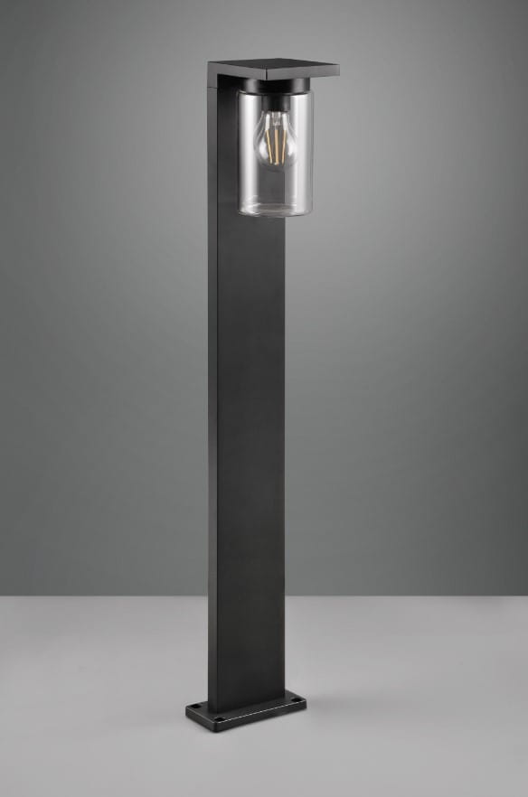 Czarna lampa zewnętrzna Ardila H100 LED o prostokątnym kształcie z przezroczystym kloszem. Ujęcie frontalne, stojąca na solidnej podstawie. Wyposażona w czujnik zmierzchu, idealna do oświetlenia przestrzeni zewnętrznych.