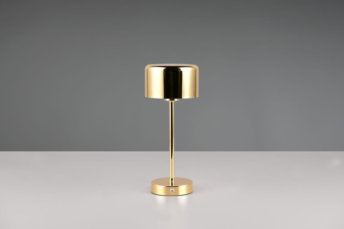 Lampa stołowa Jeff w kolorze polerowanego mosiądzu, z okrągłą podstawą i cylindryczną głowicą. Ujęcie frontalne, produkt stoi na białym tle. Widoczny przycisk na podstawie do włączania i wyłączania.